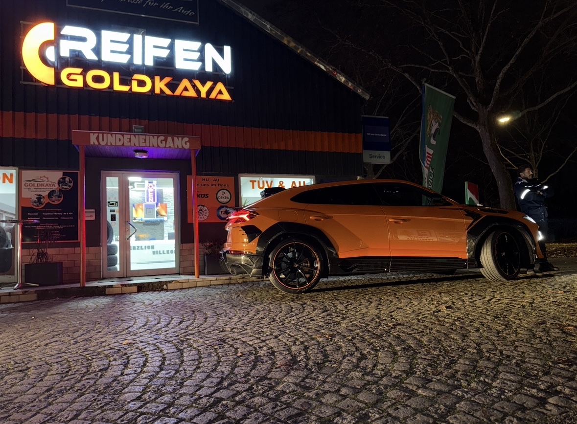 Werkstatt von Reifen Goldkaya am Abend, beleuchtete Fassade mit Sportwagen